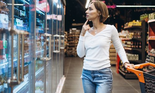 Woman shopping at the grocery store, by the refrigerator